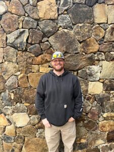 A man standing in front of a stone wall.