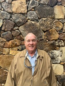 A man standing in front of a stone wall.